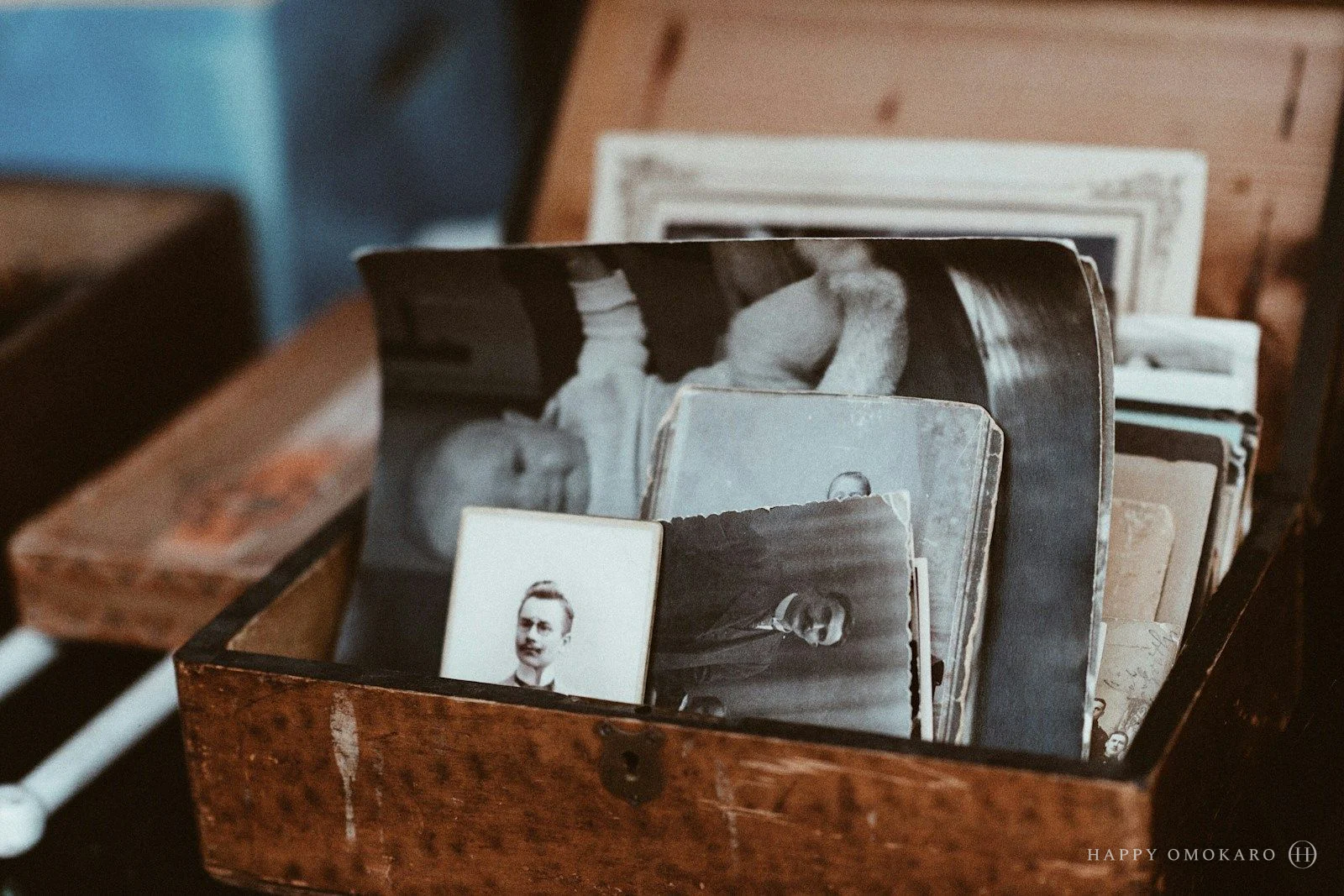 Old photographs piled inside a brown wooden chest
