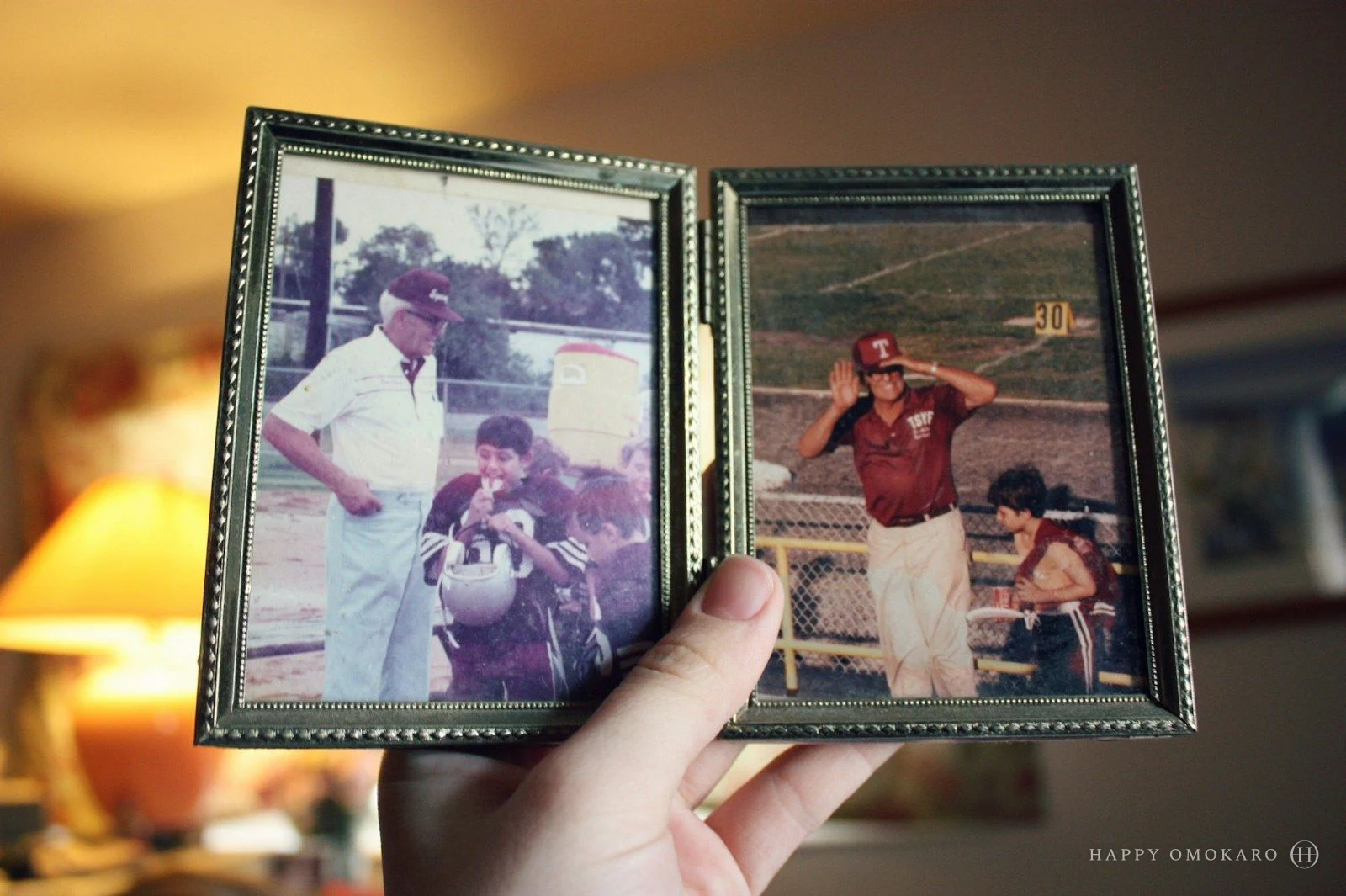 A hand holding two photographs of fathers with their sons