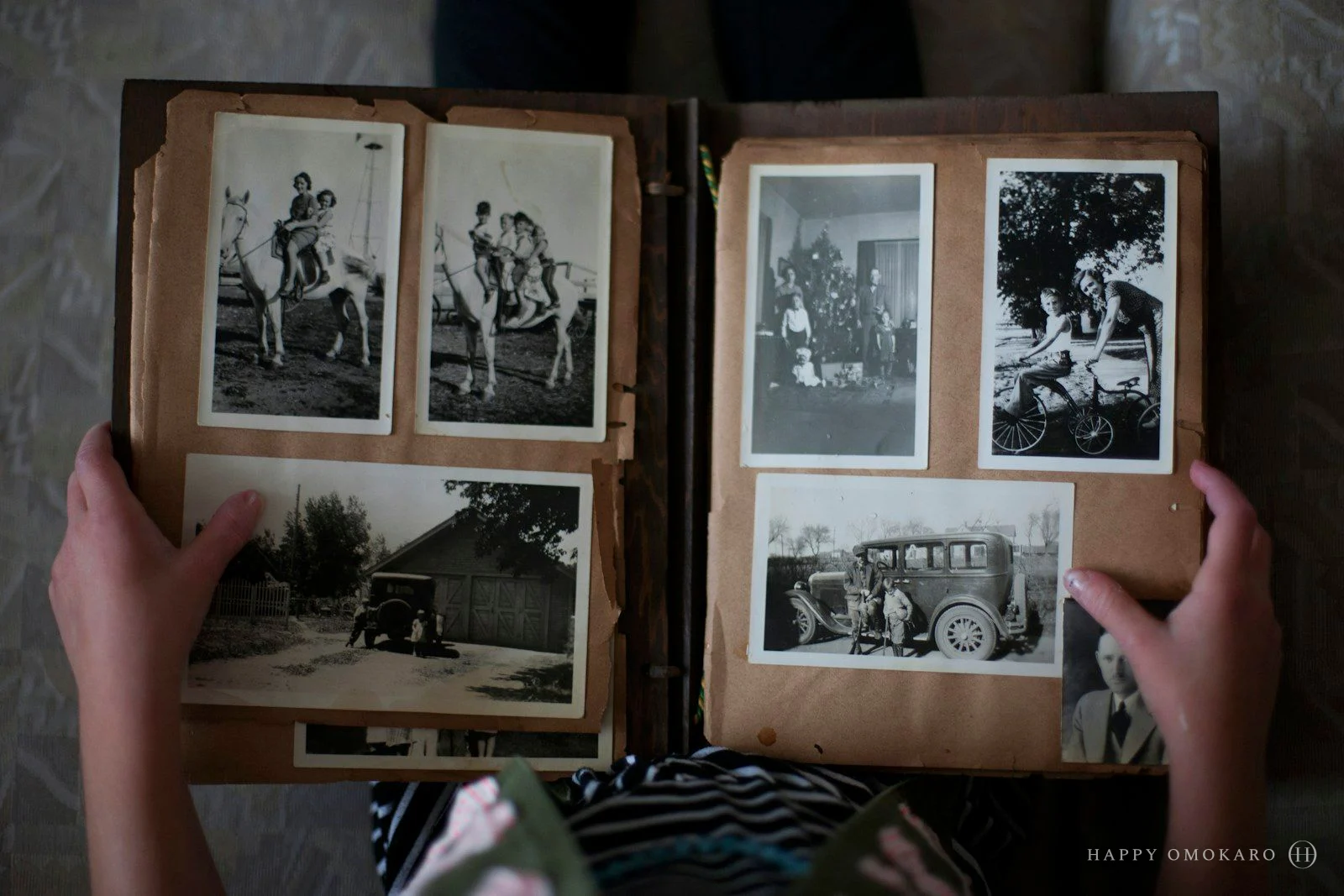Hands opening a family album filled with black and white photographs