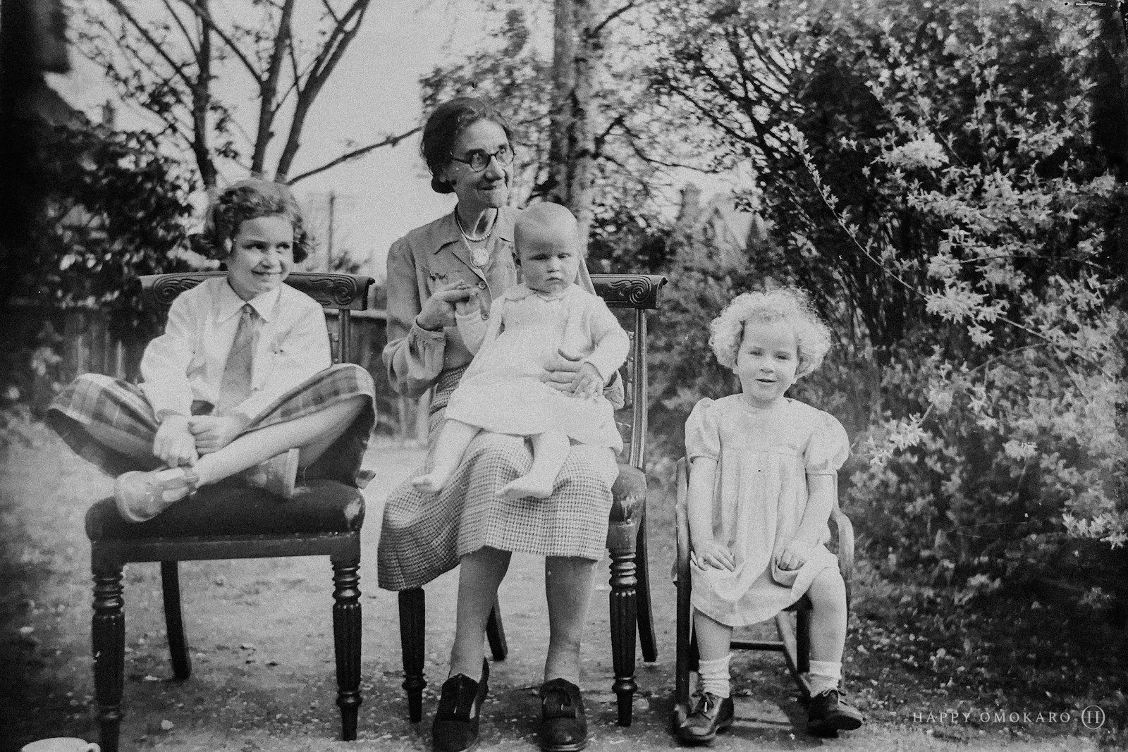 A grayscale family portrait of a mother holding a toddler with three children beside her