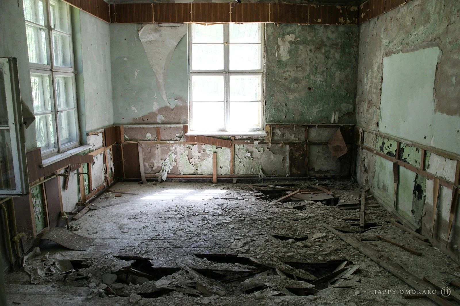 An empty ruined hall with crumbling walls and daylight falling across the floor