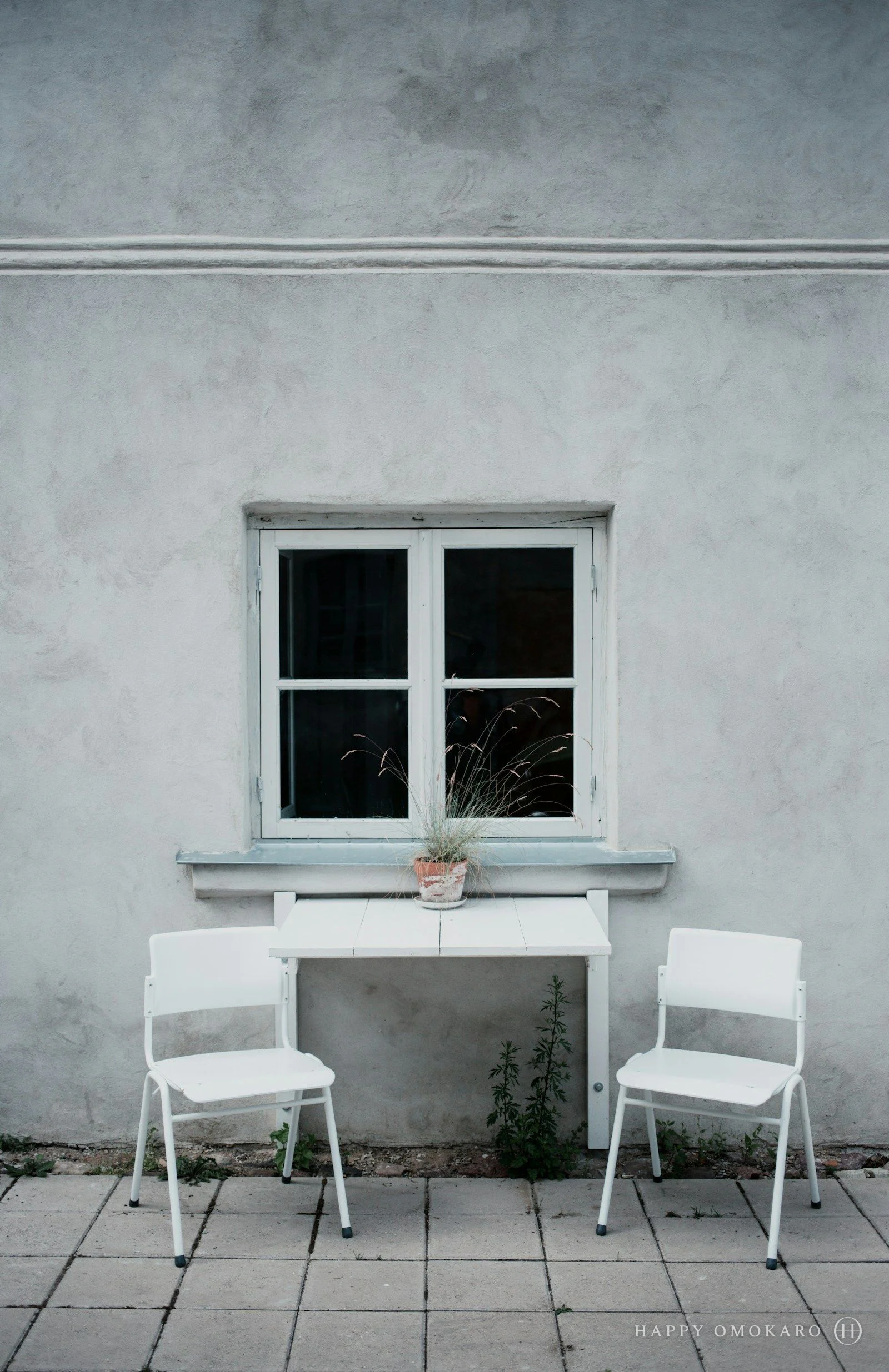 Two white folding chairs leaning against a pale wall