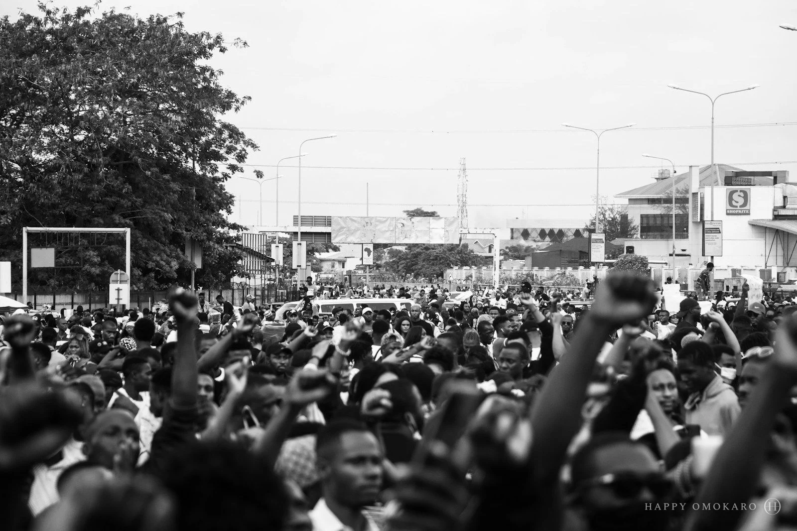 A grayscale photograph of people crossing a busy street