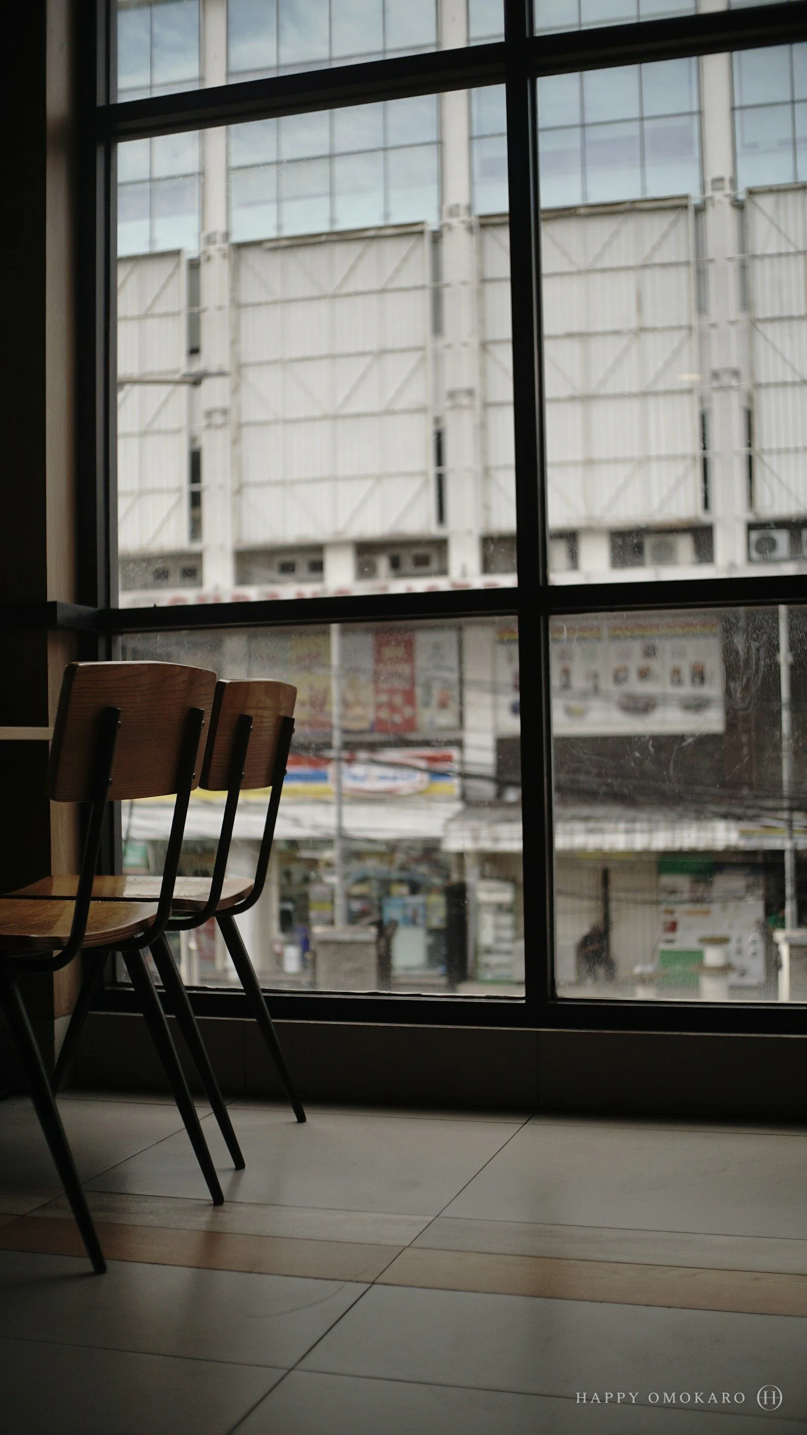 Two wooden chairs side by side in front of a tall window