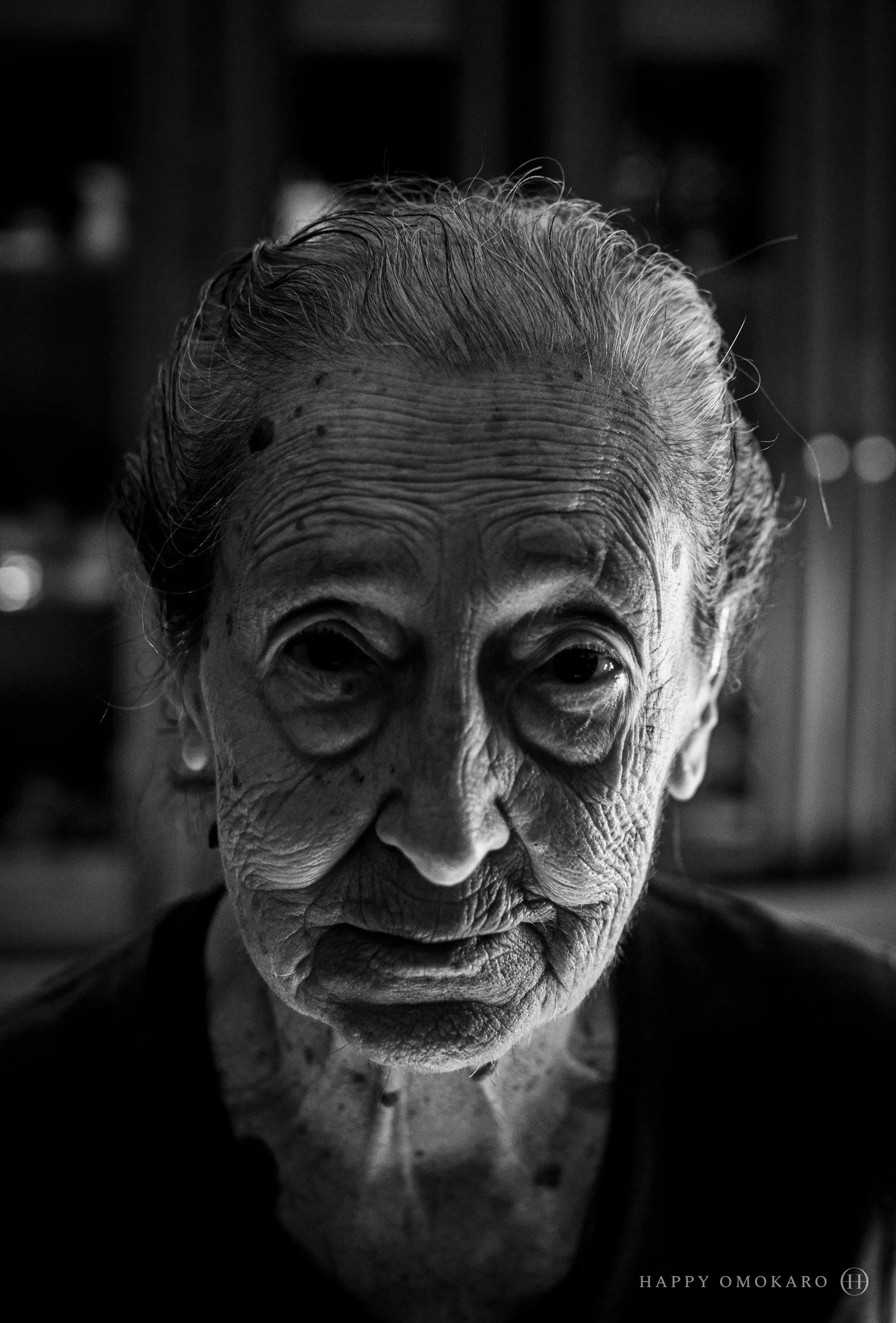 A black and white portrait of an old woman looking towards the camera