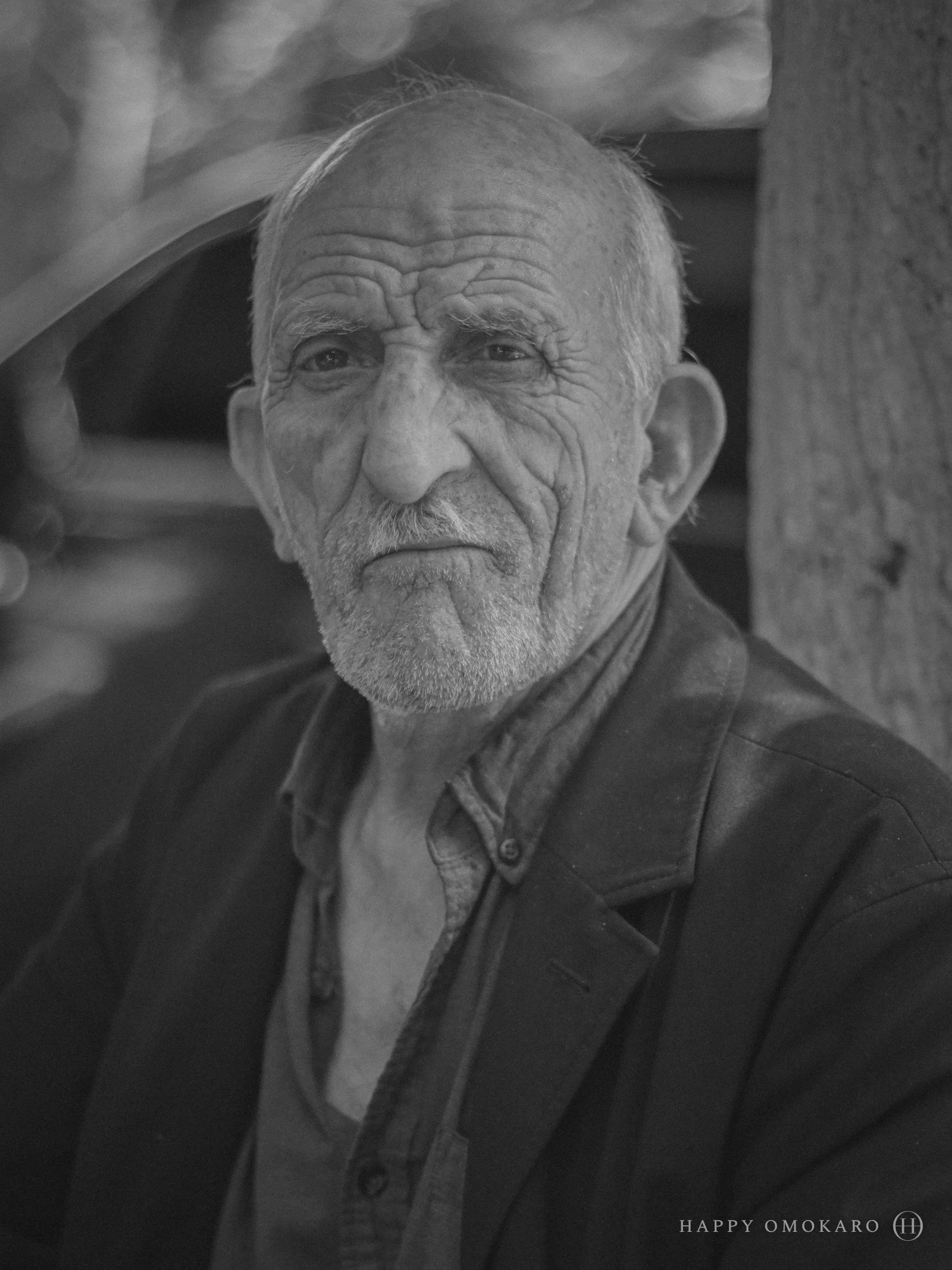 A black and white portrait of an old man, his face lit from one side