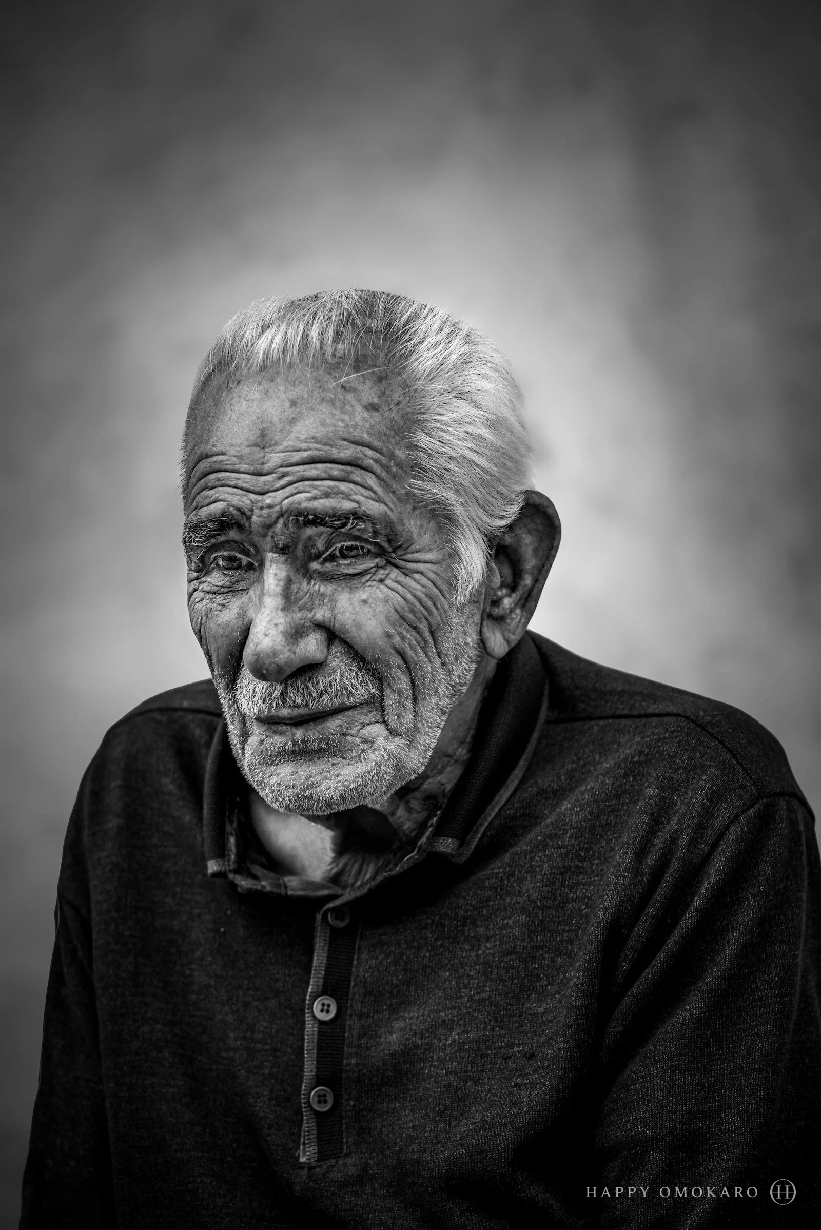 A black and white portrait of an old man in dark clothing