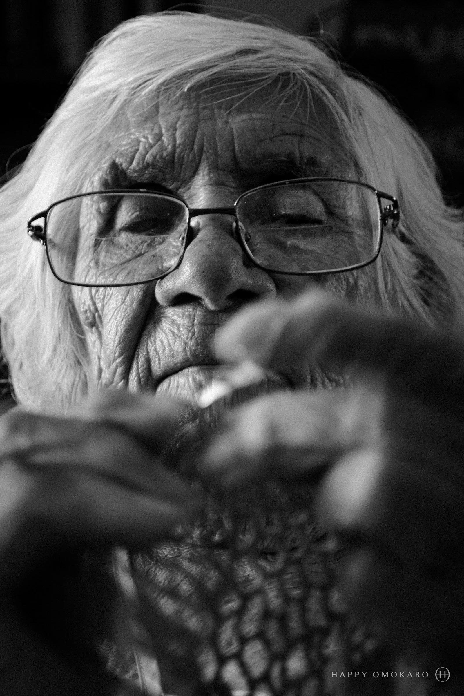 An old woman in glasses holding something gently in her hands